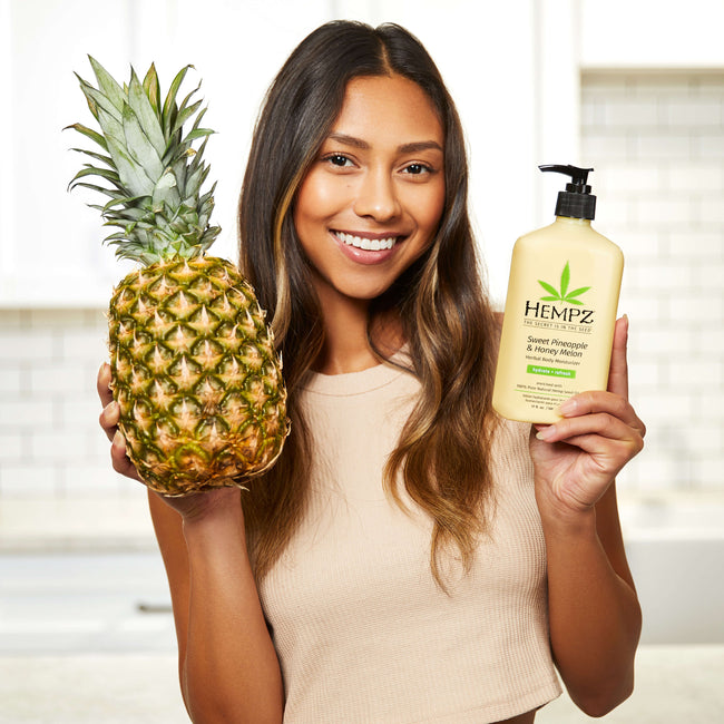 Model holding Hempz Sweet Pineapple & Honey Melon lotion with pineapple